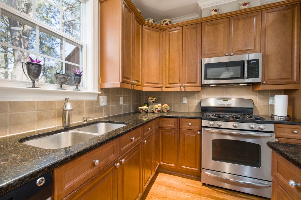 A well-lit modern kitchen featuring wooden cabinets and stainless steel appliances.